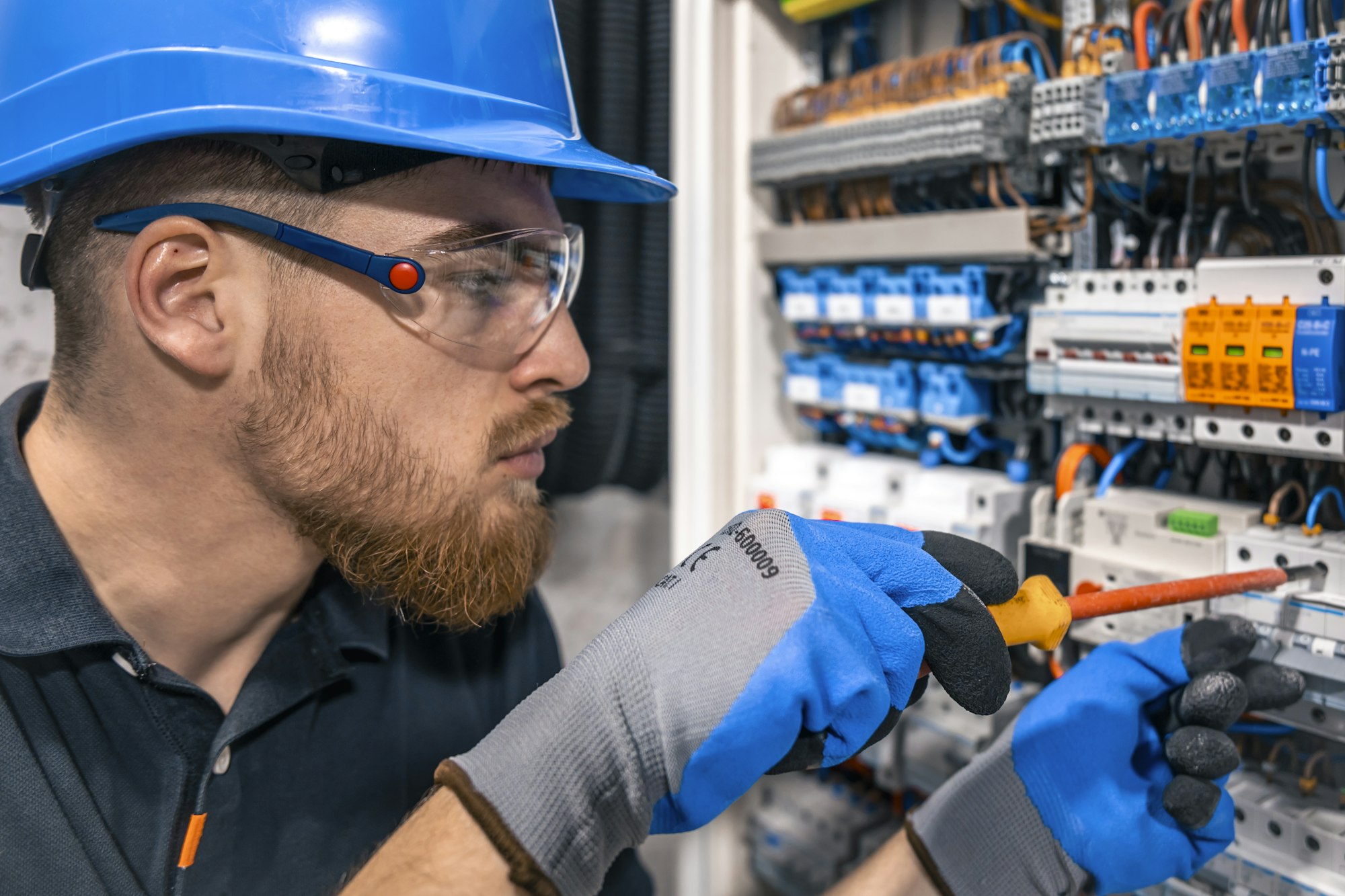 Male electrician working in a switchboard with fuses.